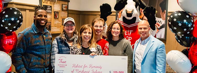 People from the Habitat for Humanity of Northwest Indiana organization standing together smiling with a Chick-fil-A and holding a large check