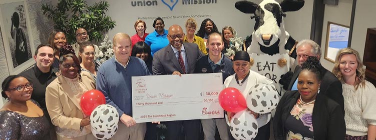 People from the Union Mission organization standing together smiling with a Chick-fil-A and holding a large check