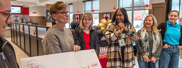 A group of people from the Journey to Dream Foundation standing together and holding a large check