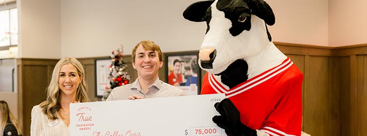 Two people from the Coffee Oasis standing together with a Chick-fil-A Cow and holding a check and smiling