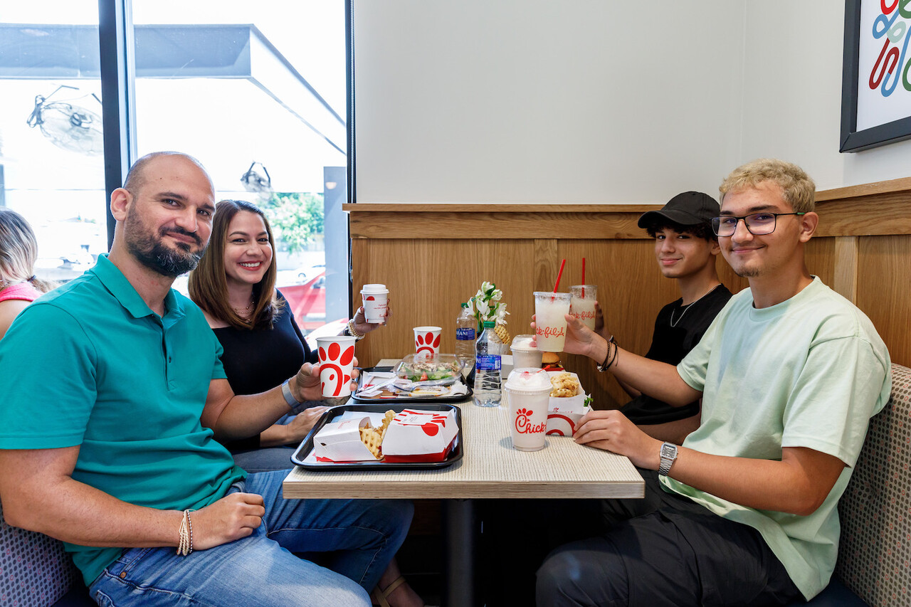 Four people smiling and sitting at Chick-fil-A restaurant booth